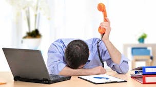 Man on the phone in despair while sitting at a laptop