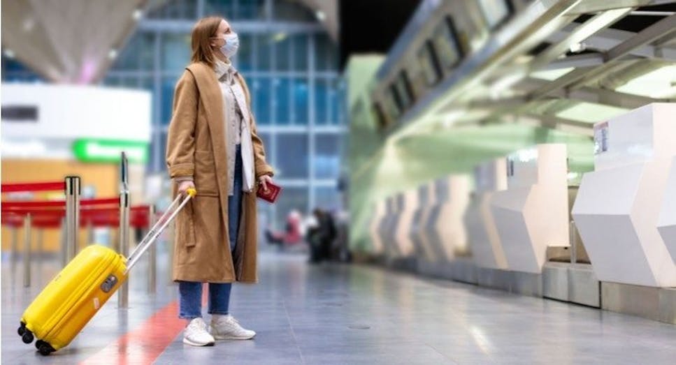 A traveler at the airport, passport in hand, looks for the check-in counter