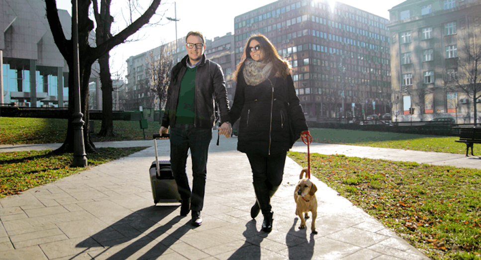 Couple walking with suitcase and dog