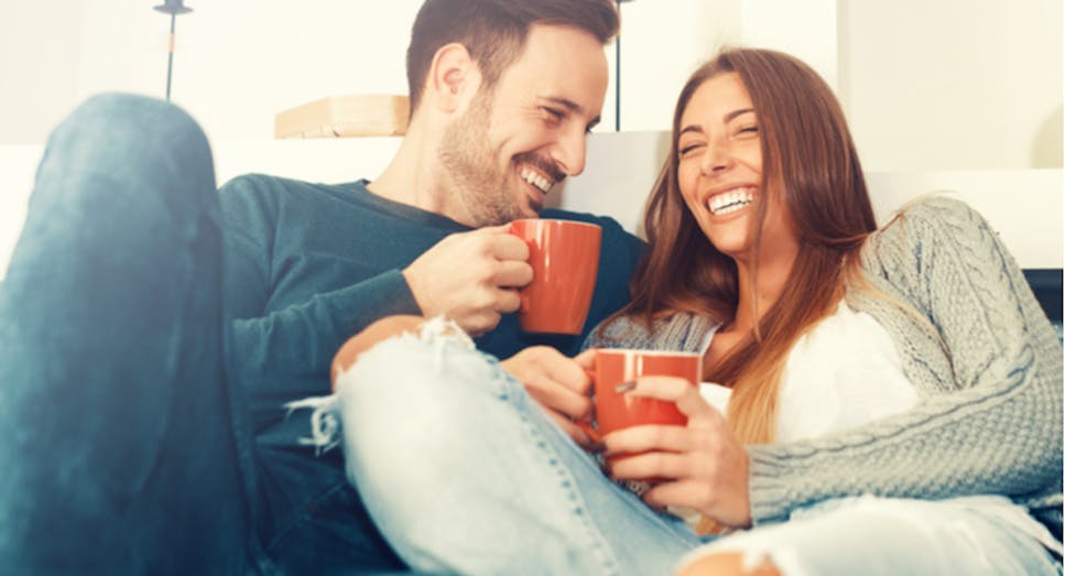 Couple sitting together drinking tea on sofa