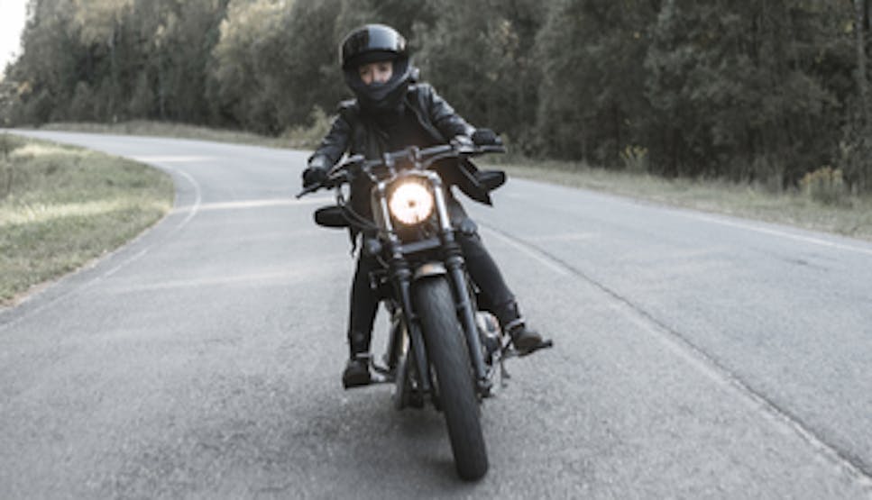 Phot of a woman on a motorbike riding down a road