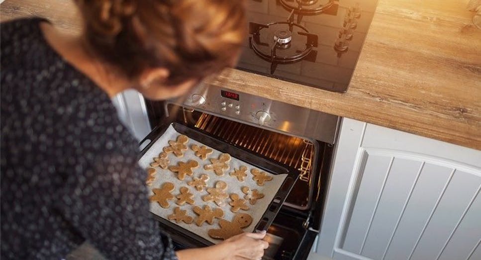 Woman putting gingerbread into oven 