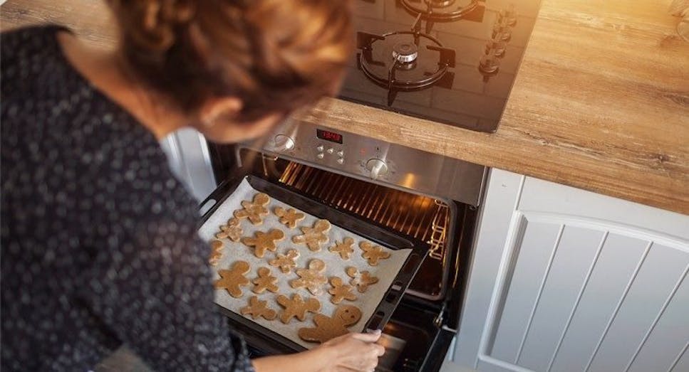 Woman putting gingerbread into oven