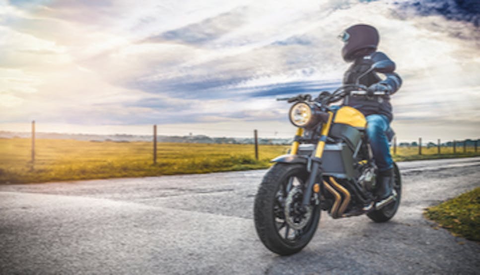 person on a motorcycle with a helmet on looking towards a field