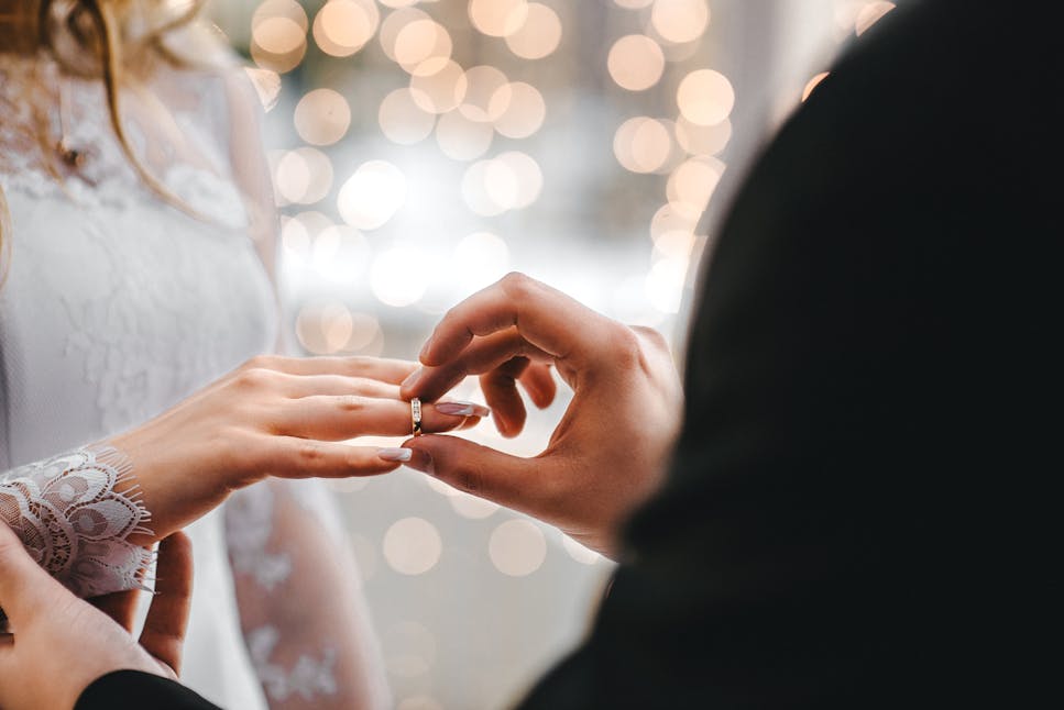 groom putting wedding ring on bride's finger