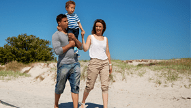 couple walking on the beach with their child 