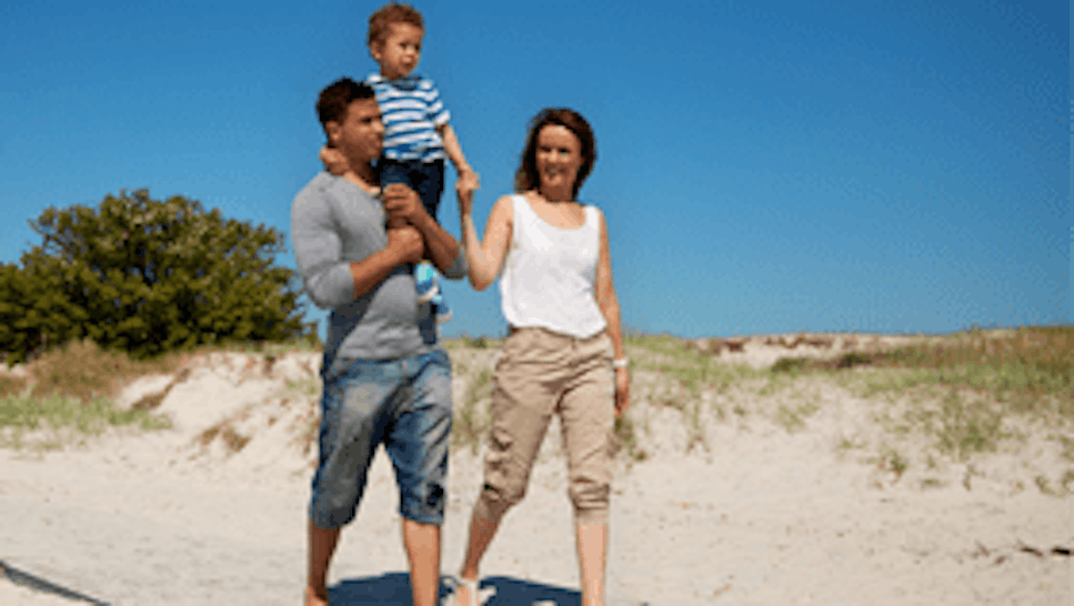 couple walking on the beach with their child