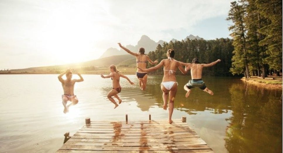 Group of friends jumping into the lake