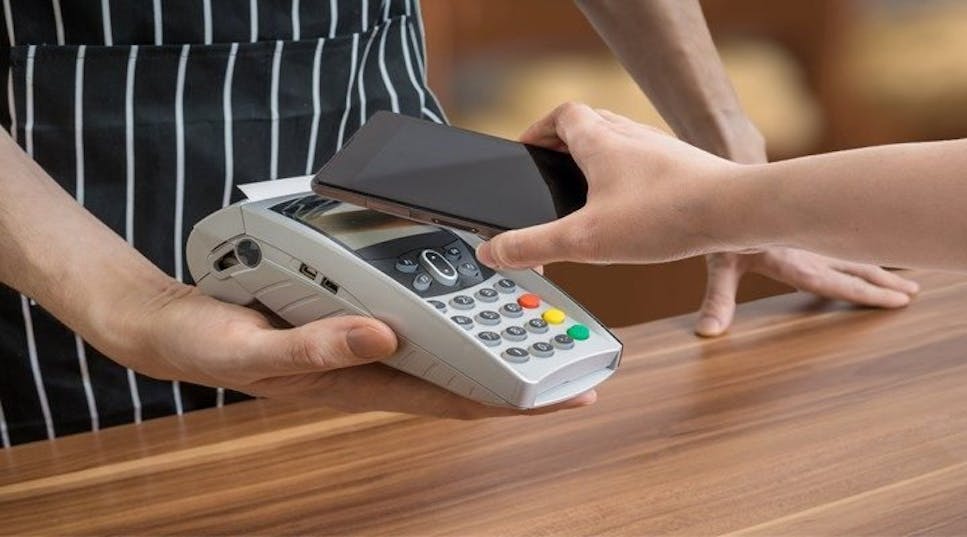 Holding Iphone over contactless card reader to pay using Apple Pay