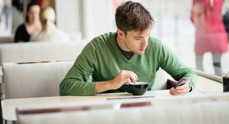 Man at a cafe looking at his phone