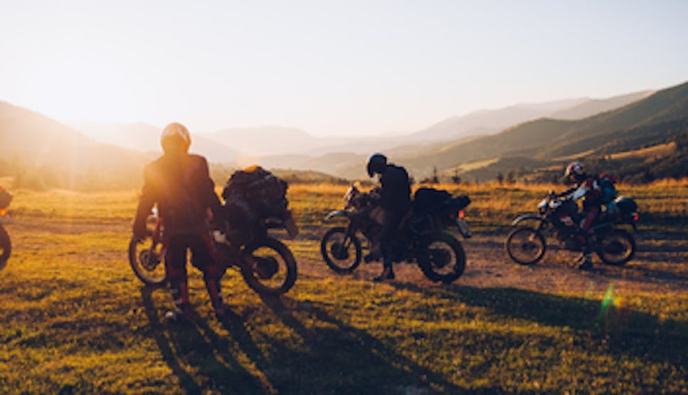 People on motorbikes on a hill with a sunset in the background
