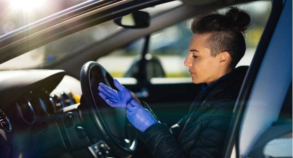 woman in car putting on ppe gloves