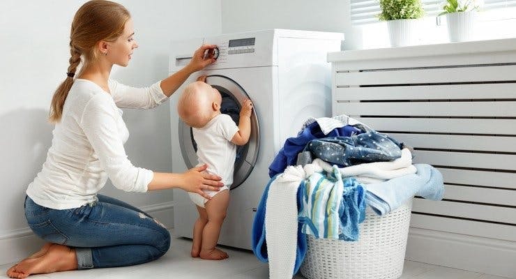 Mother and child loading washing into machine