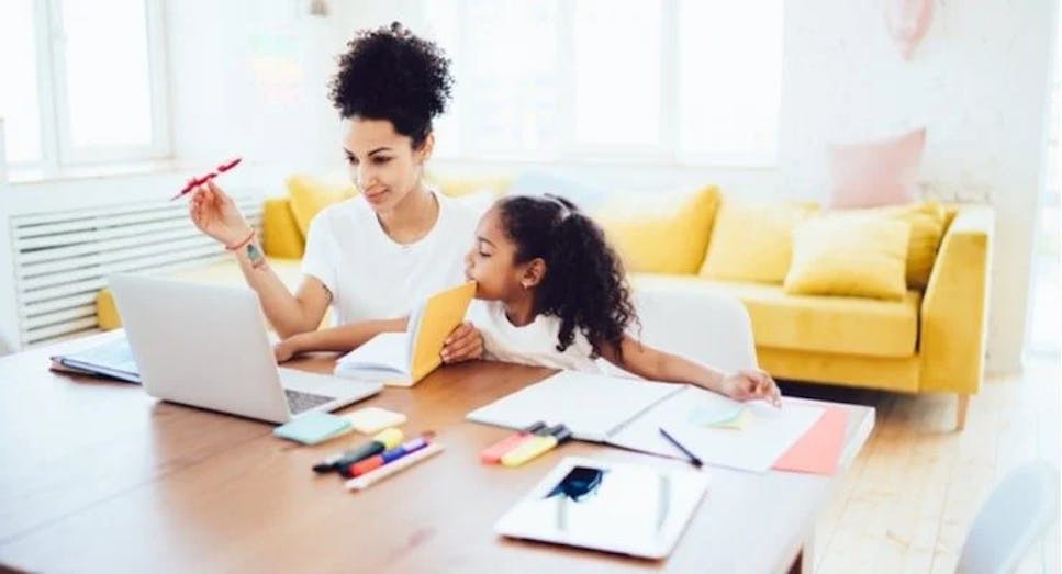A woman working from home sat with a child doing her homework
