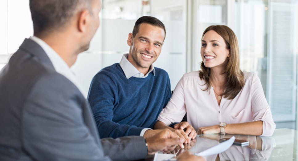 A couple in an office listen to their financial advisor across the desk
