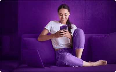 girl sitting on a purple sofa looking at a phone