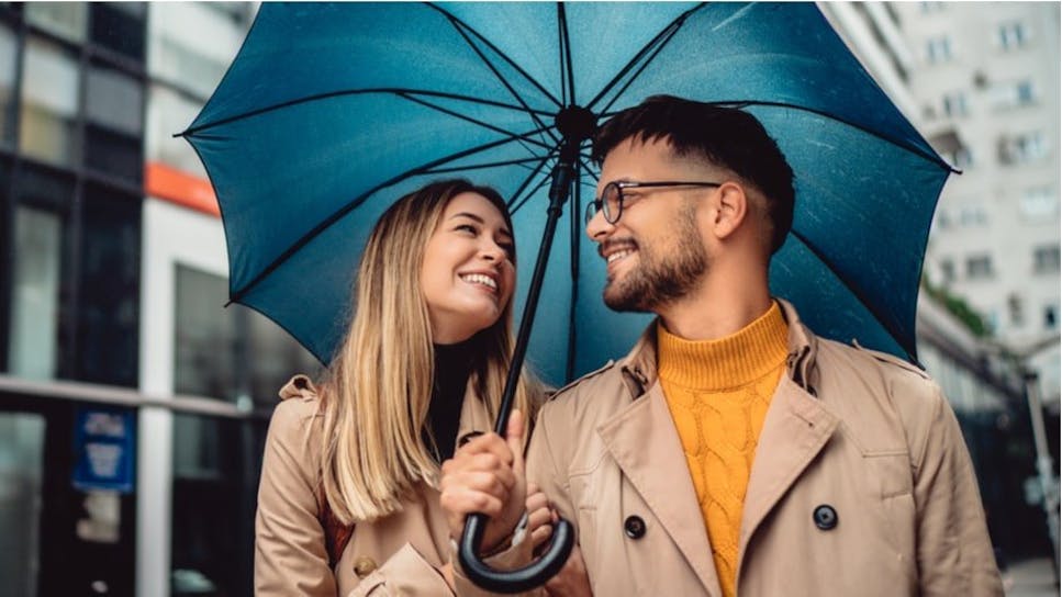 man and woman smiling under umbrella