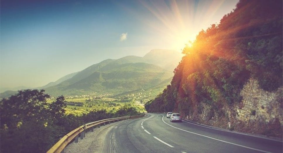 view of a road bend and a sunny mountain range in Montenegro, Europe