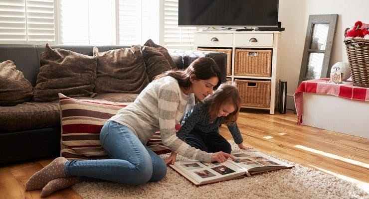 mother and daughter in a living room looking at a photo album