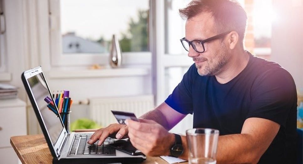 Man using credit card to pay via a laptop