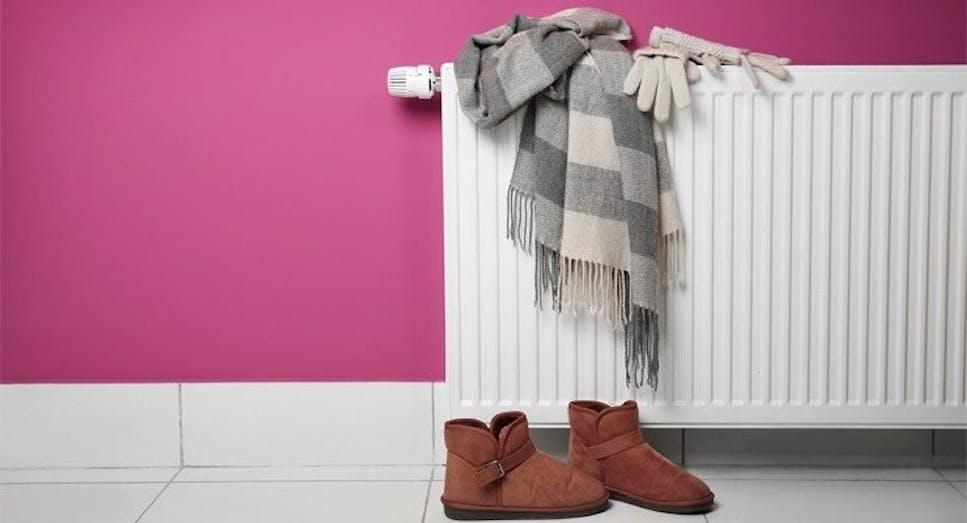 Scarves and a pair of boots drying against a radiator 