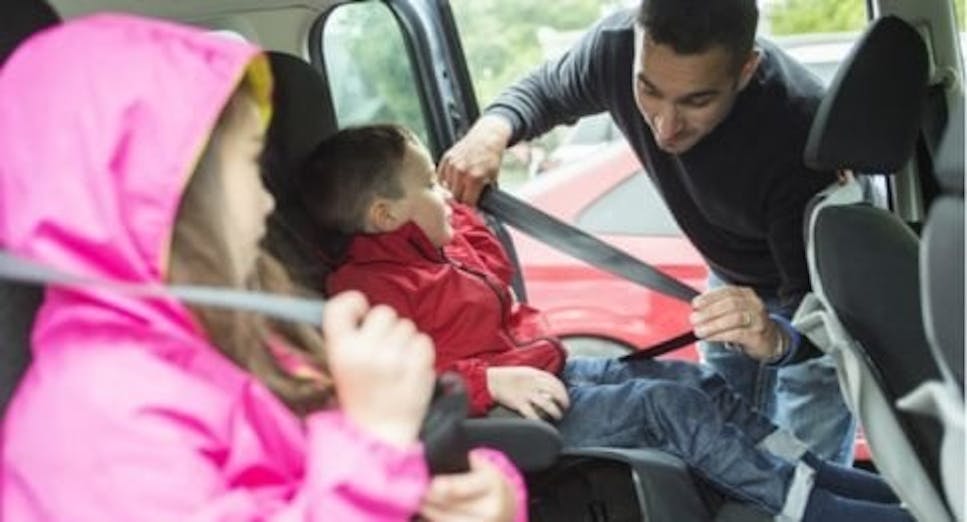 Man putting children in car seats