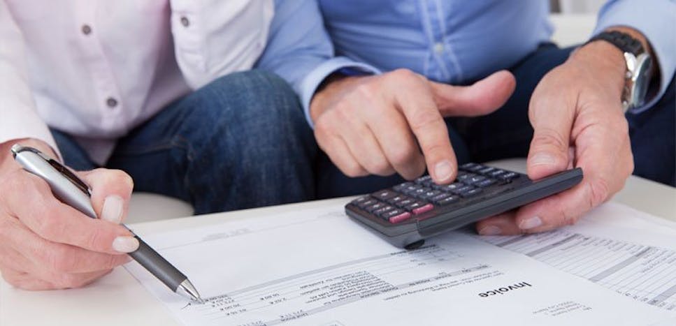 Two office workers check an invoice
