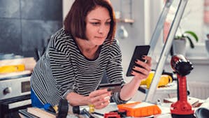 Woman looking at mobile phone with work tools around her