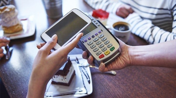 Holding mobile phone over contactless card reader to pay using Android Pay