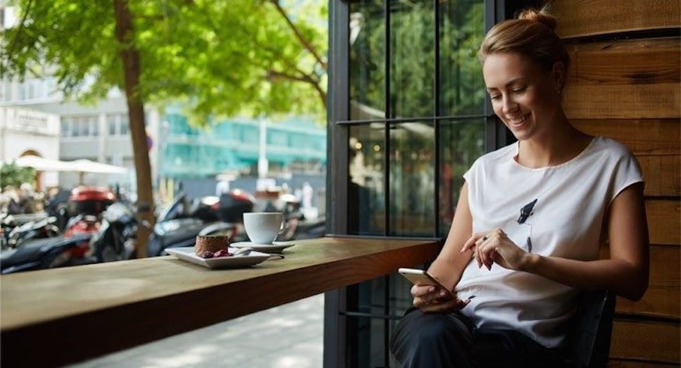 Woman using mobile phone outside cafe