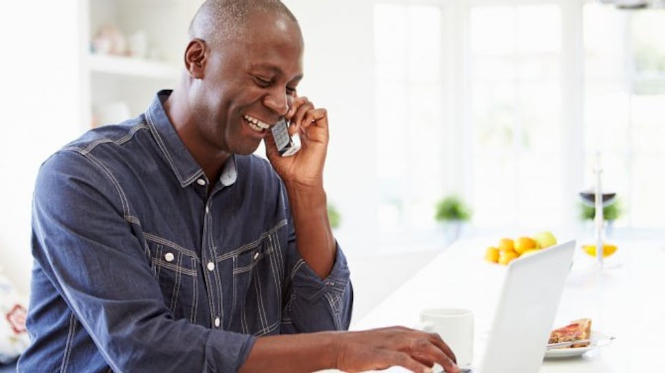 happy man on phone using laptop