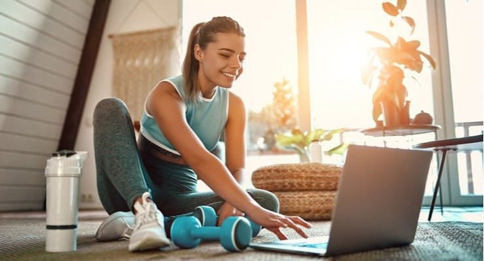 Girl using laptop in home whilst exercising