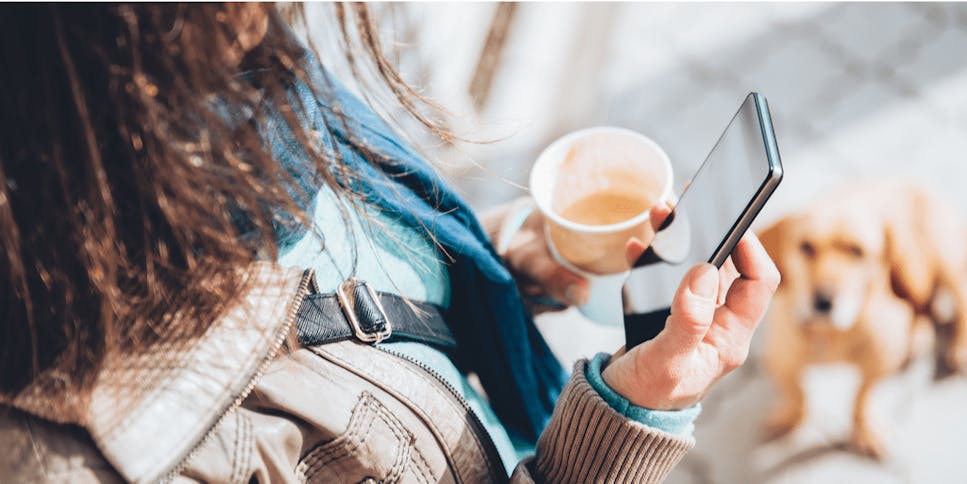 Close up of female hands holding phone and a takeaway coffee