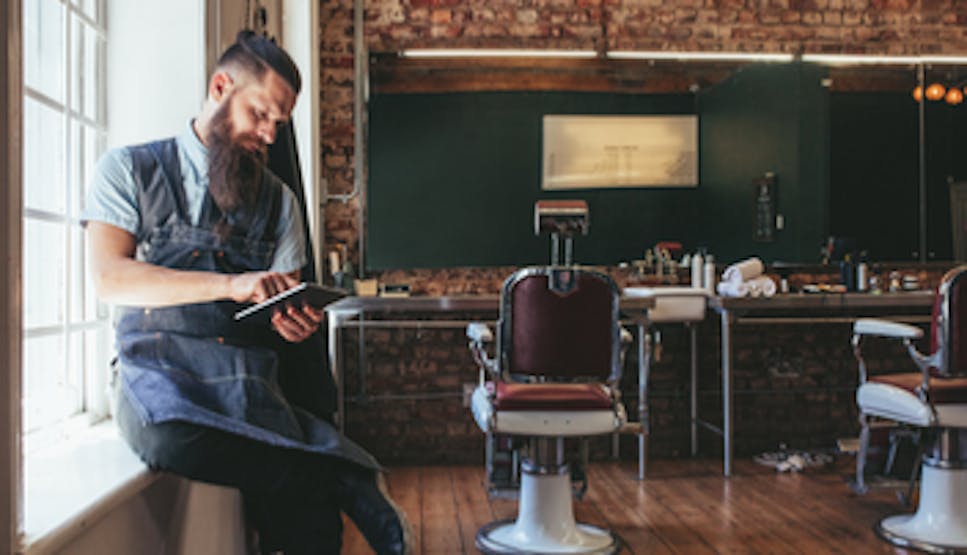Picture of a barber looking at a tablet computer in a barber shop