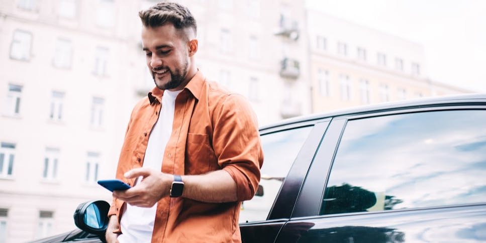 Young male driver leaning against his car