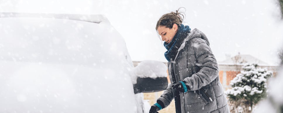 woman standing next to snow covered car