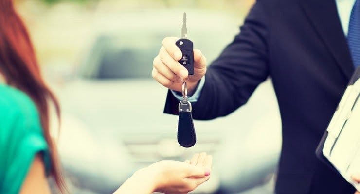 Cars salesman proffers car key to client