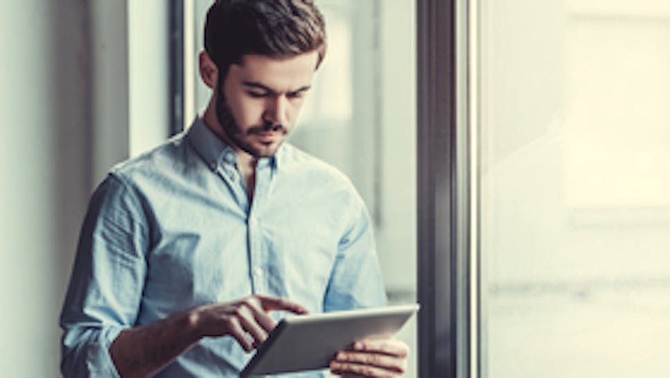 A man in a blue shirt looking at a tablet device