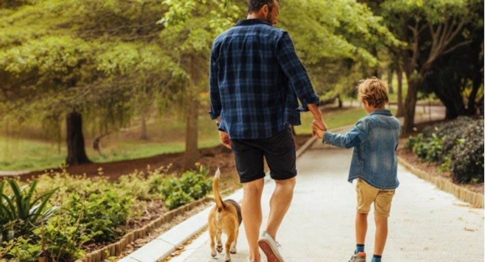 Man and child walking dog in forest