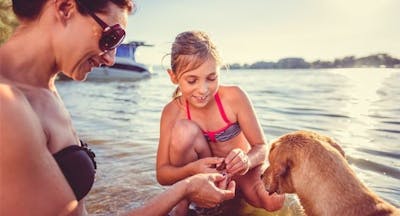 mother, daughter, and dog on the beach