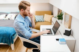 Man at desk working on laptop in bedroom
