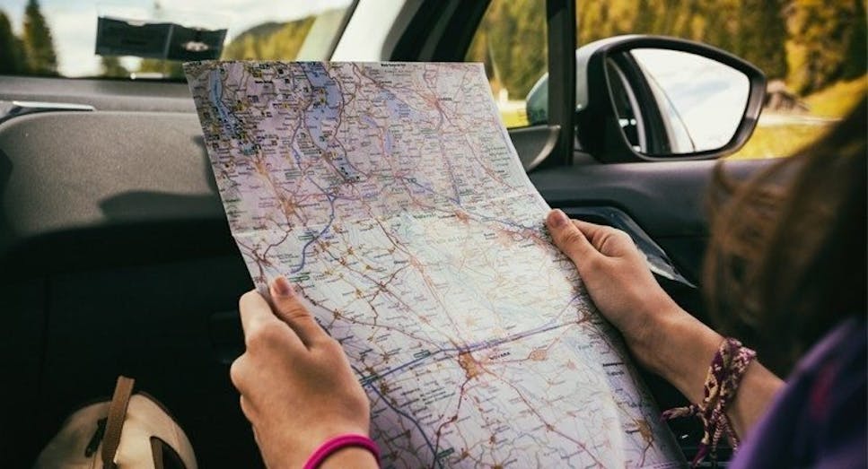 Passenger reading a map in the backseat of a car