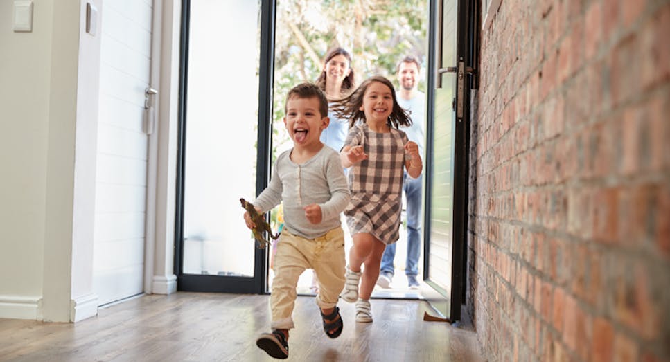 a boy and girl running into house with parents behind