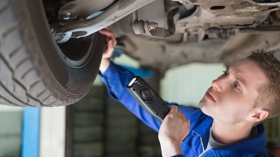 a mechanic inspecting the underneath of a car