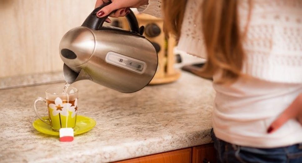 Woman pouring drink into cup using kettle