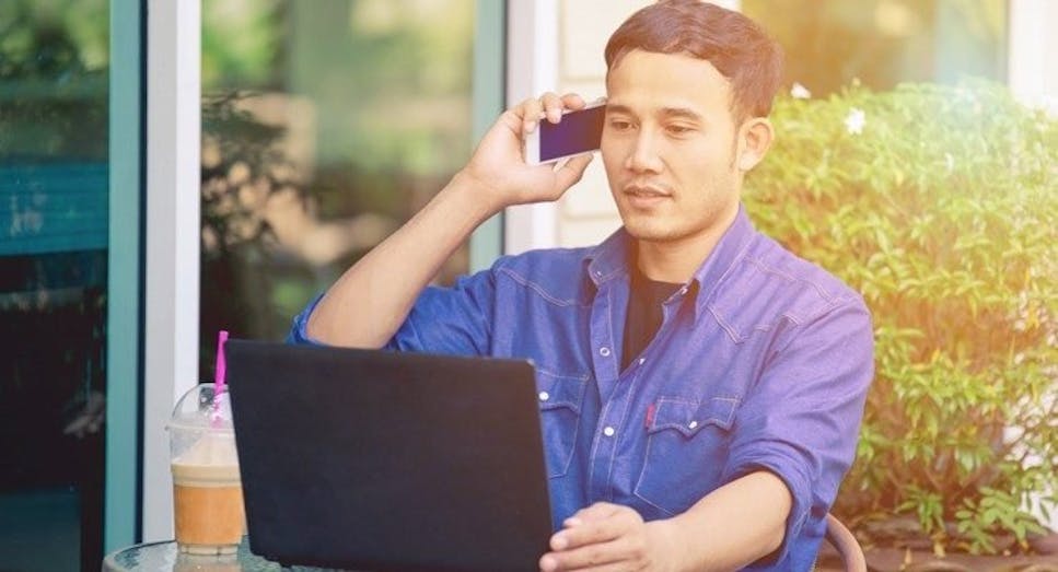 Man talking on mobile whilst on laptop