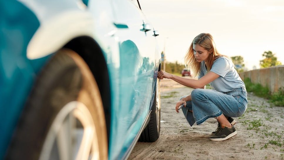 Woman checking car tyres