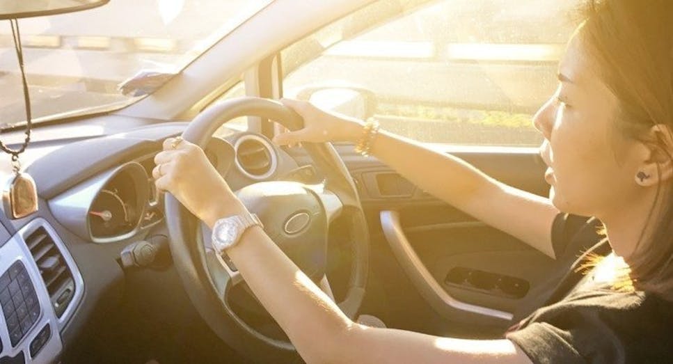 Person driving car on road in summer