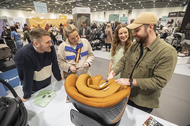 Image of a man showing a baby seat to three members of the public at a previous Baby Show