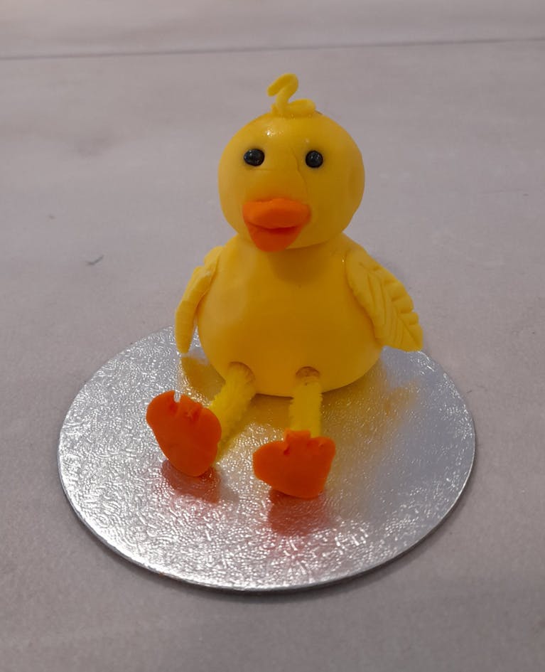 Yellow chick or duckling made with cake icing, on a round silver base